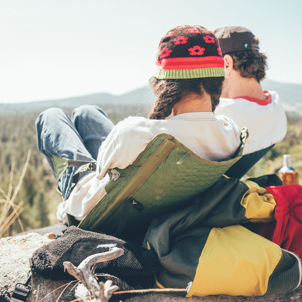 Two people lounging on the top of a rock looking out over mountains while sitting in comfy camping chairs
