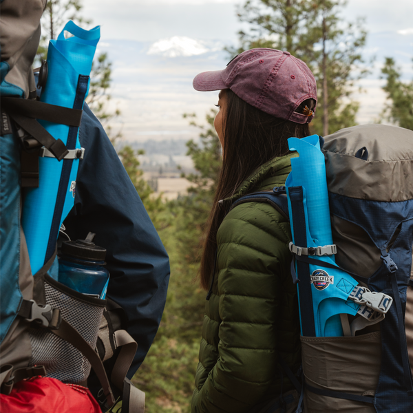 An inflatable chair rolled up and stored compactly in a backpack side waterbottle pouch