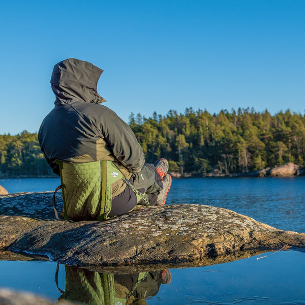 Man sitting in front of a lake in his olive green hex 2.0 chair