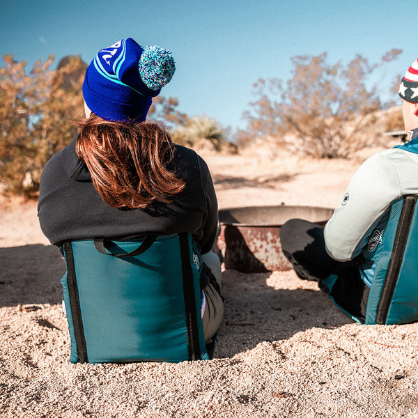 Two people sitting next to a fire ring sitting in their lightweight casual chairs