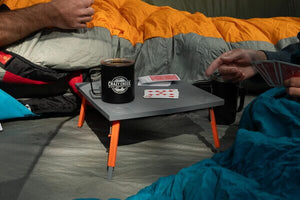 Crazy Creek foldable table in a tent with two people playing cards