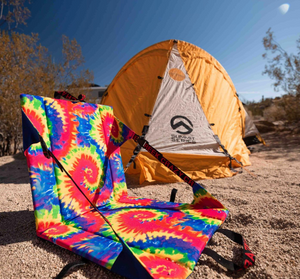 Tie Dye crazy Creek chair in front of a tent in the desert