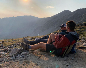 two friends reclining in their crazy creek chairs at the top of a mountain hike