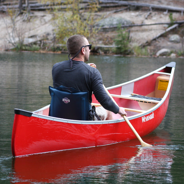 Man paddling a canoe on a beautiful lake while he is sitting in a comfortable canoe chair