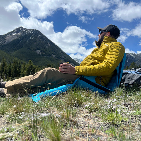 Man sitting in a comfortable AirLounger in front of large green mountains