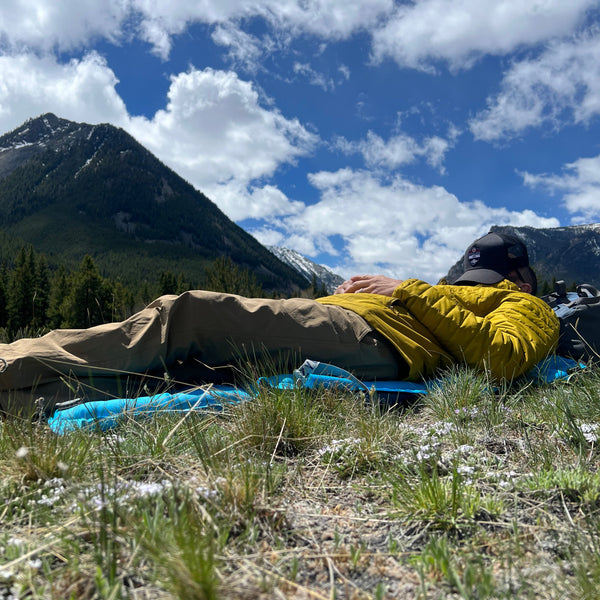Man taking a nap on his comfortable inflatable chair sleeping pad in the mountains