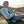 Man sitting in a green chair while looking at his phone on a mountain