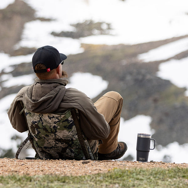 Man sitting in a camo chair relaxing in snowy mountains