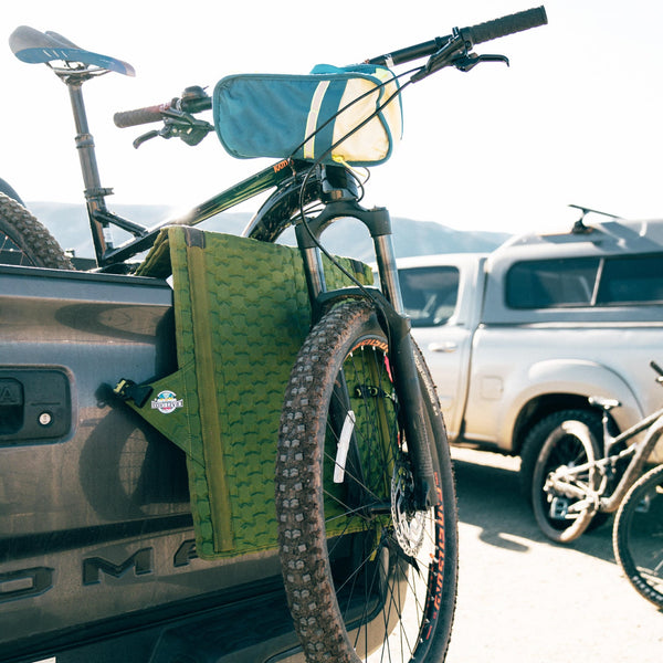 Hex 2.0 Crazy Creek chair being used as a tailgate pad for a mountain bike on a truck