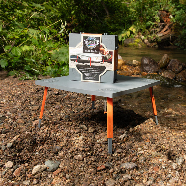 Crazy Creek table unfolded next to a river in a forest