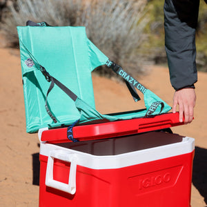 Crazy Creek chair strapped on to an ice chest at camp turning it into a tall chair