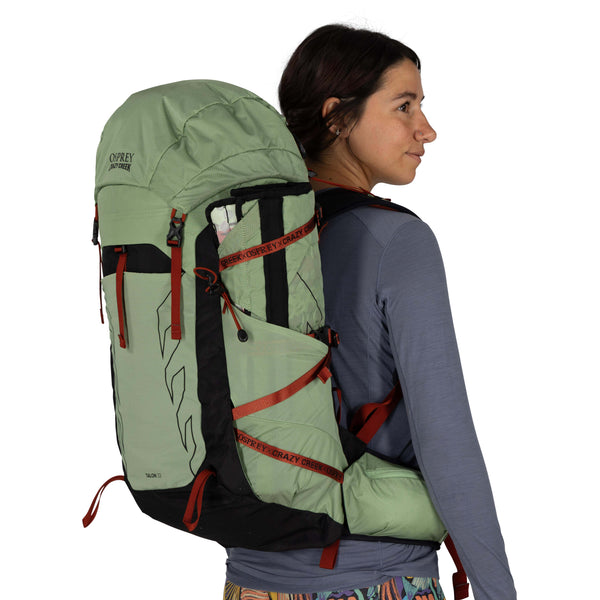 Backpacking woman carrying the Osprey and Crazy Creek Collab Backpack on white