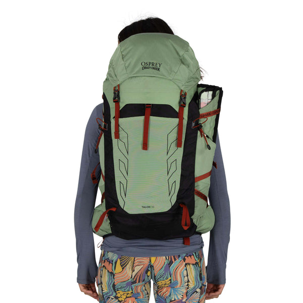 Backpacking woman carrying the Osprey and Crazy Creek Collab Backpack on white - Back of pack