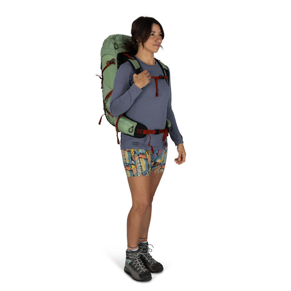 Backpacking woman carrying the Osprey and Crazy Creek Collab backpack full body on white