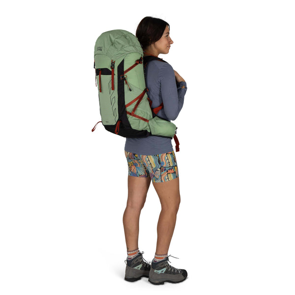 Backpacking woman carrying the Osprey and Crazy Creek Collab backpack full body on white - facing away