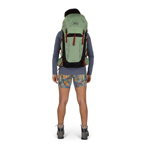 Backpacking woman carrying the Osprey and Crazy Creek Collab backpack full body -looking at back - on white
