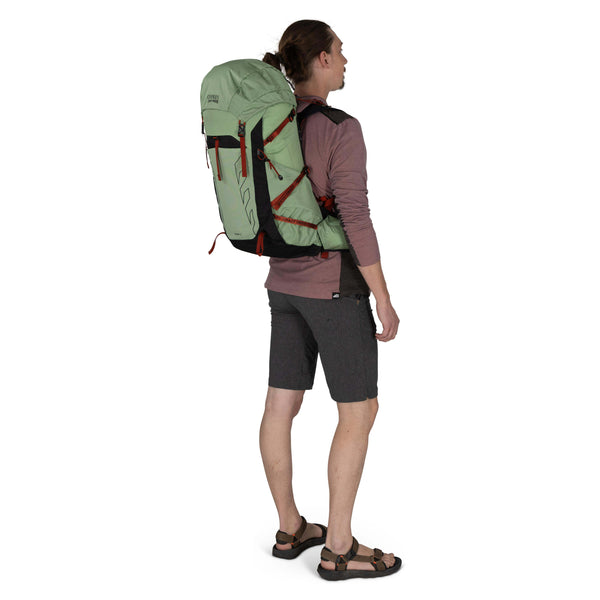 Backpacking man carrying the Osprey and Crazy Creek Collab backpack full body on white - 3.4 facing away